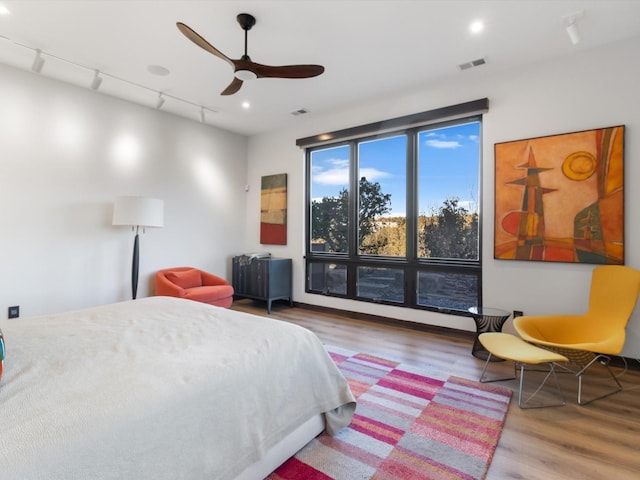 bedroom featuring hardwood / wood-style flooring, ceiling fan, and track lighting