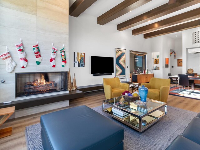 living room featuring a fireplace, hardwood / wood-style flooring, and beamed ceiling