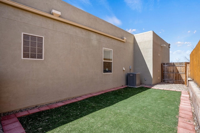 back of property with stucco siding, cooling unit, a yard, and fence