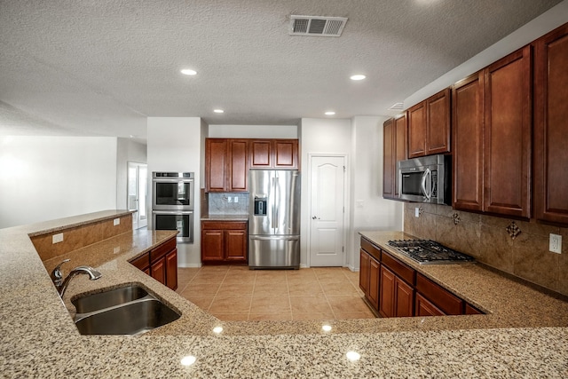 kitchen featuring visible vents, a sink, tasteful backsplash, appliances with stainless steel finishes, and light tile patterned floors