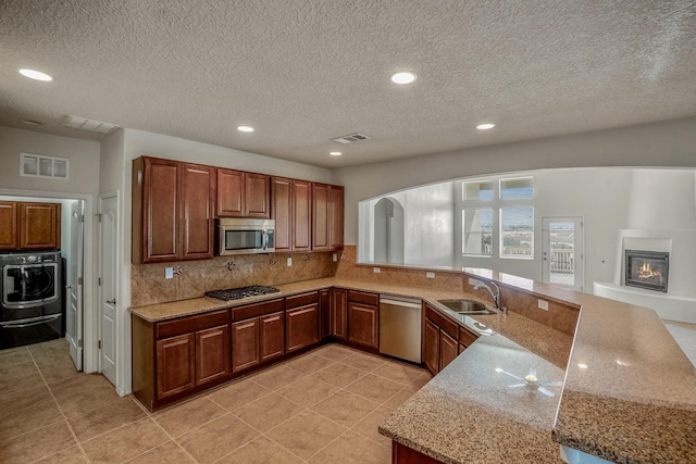 kitchen featuring washer / dryer, visible vents, appliances with stainless steel finishes, and a sink