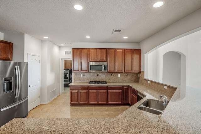 kitchen featuring visible vents, a sink, stainless steel appliances, light tile patterned floors, and decorative backsplash