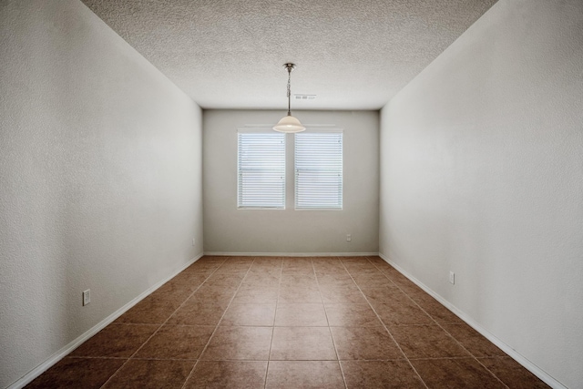 empty room featuring tile patterned flooring, baseboards, visible vents, and a textured ceiling