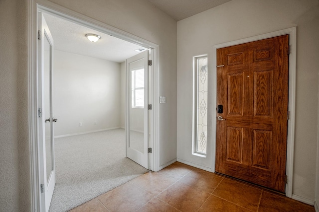 carpeted foyer featuring tile patterned flooring and baseboards