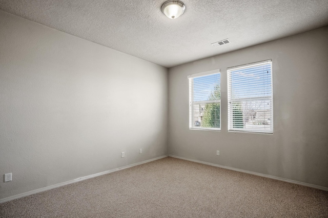 carpeted spare room featuring baseboards, visible vents, and a textured ceiling