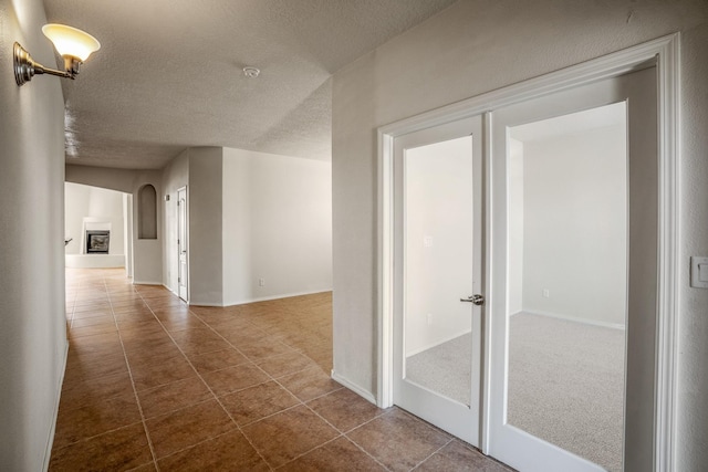 hall with dark tile patterned flooring, arched walkways, and a textured ceiling