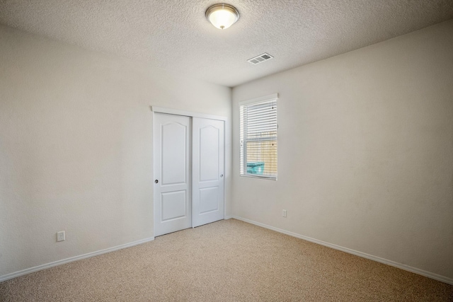 unfurnished bedroom with light colored carpet, visible vents, a closet, and baseboards