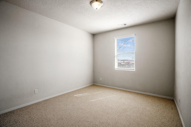 spare room with baseboards, light colored carpet, visible vents, and a textured ceiling