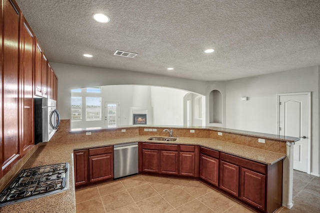 kitchen featuring visible vents, a peninsula, recessed lighting, a sink, and appliances with stainless steel finishes