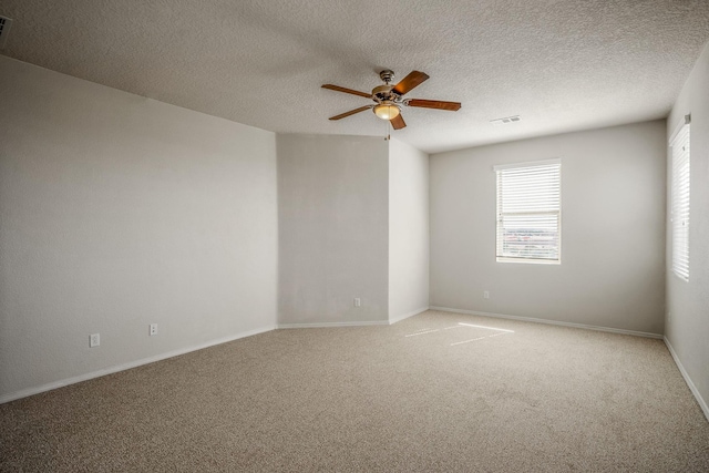 empty room featuring baseboards, visible vents, ceiling fan, a textured ceiling, and light carpet