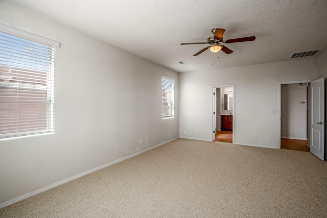 unfurnished bedroom with visible vents, a textured ceiling, ensuite bath, carpet floors, and baseboards