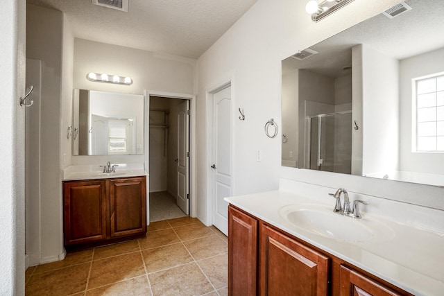 bathroom featuring a sink, a textured ceiling, and a shower stall