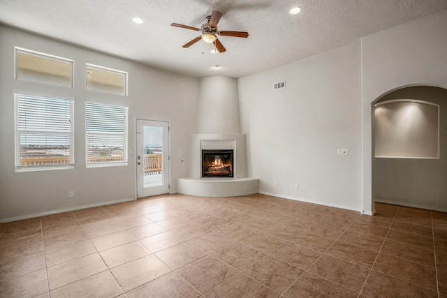 unfurnished living room featuring tile patterned floors, visible vents, a textured ceiling, a fireplace, and ceiling fan