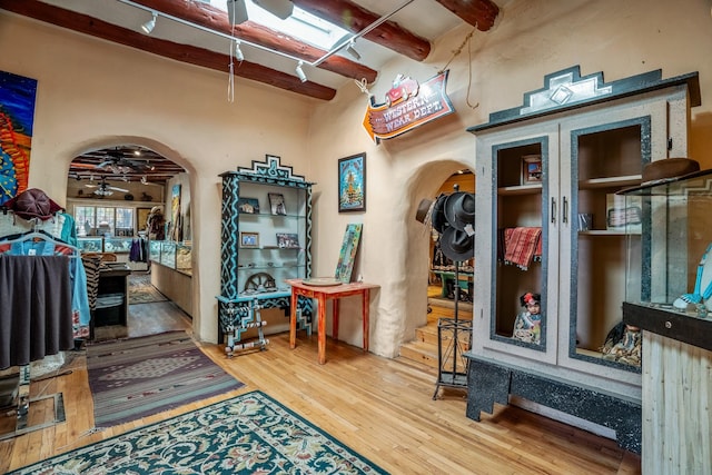 interior space with ceiling fan, beam ceiling, and wood-type flooring