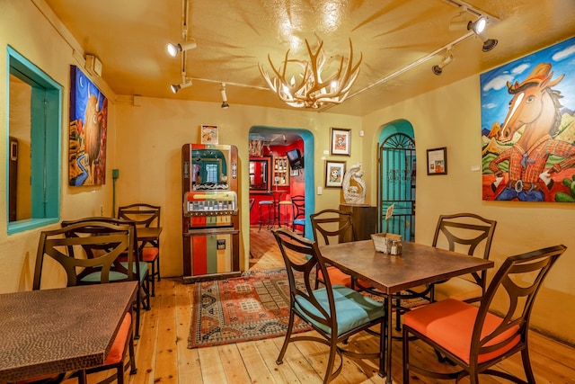 dining space featuring light wood-type flooring, rail lighting, and a chandelier