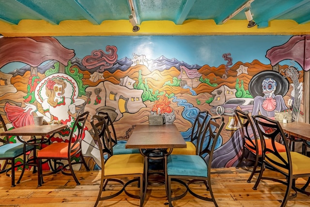 dining space with hardwood / wood-style floors and beamed ceiling