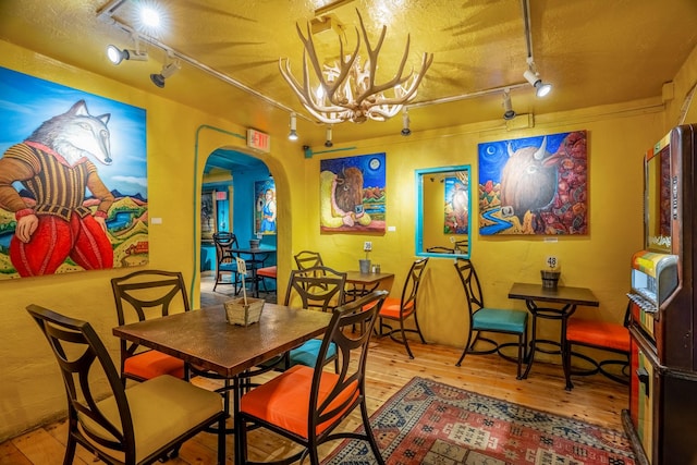 dining area featuring hardwood / wood-style floors, a chandelier, a textured ceiling, and track lighting