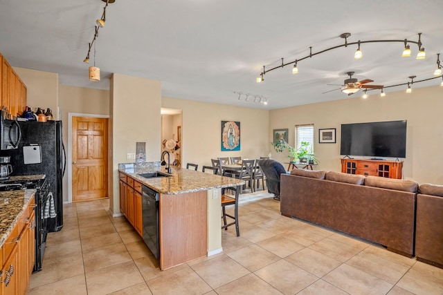 kitchen featuring a kitchen breakfast bar, ceiling fan, sink, black appliances, and decorative light fixtures