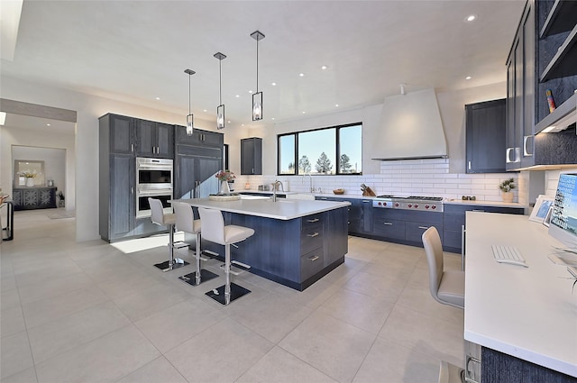kitchen featuring extractor fan, open shelves, an island with sink, decorative backsplash, and light countertops