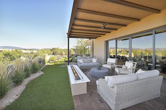 view of patio / terrace with a mountain view and an outdoor living space with a fire pit