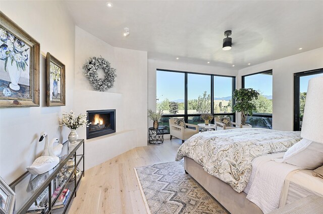 bedroom with wood finished floors, a lit fireplace, and recessed lighting