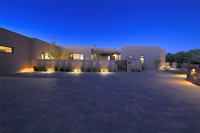 view of front of home with a gate, stucco siding, and fence