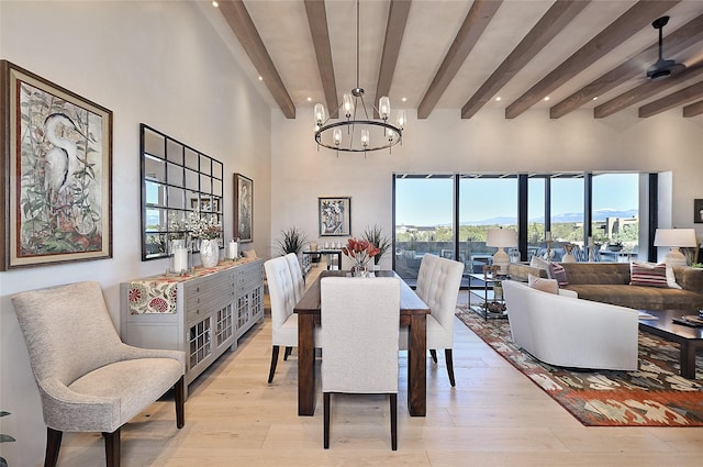 dining area with beam ceiling, a chandelier, recessed lighting, light wood-type flooring, and a towering ceiling