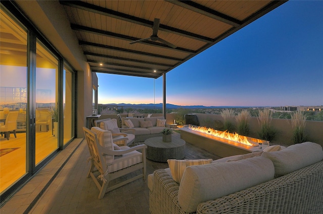 patio terrace at dusk with outdoor lounge area, a mountain view, and ceiling fan