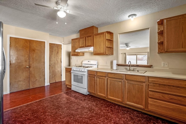 kitchen with gas range gas stove, sink, ceiling fan, a textured ceiling, and dark carpet