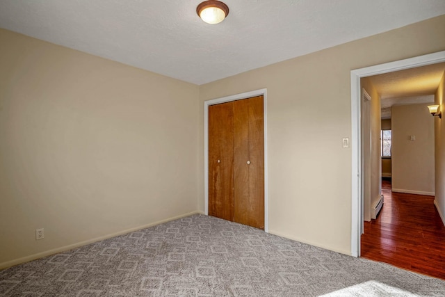 unfurnished bedroom featuring carpet flooring, a baseboard radiator, and a closet