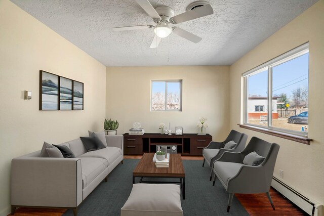 living room with ceiling fan, dark hardwood / wood-style flooring, a textured ceiling, and a baseboard radiator