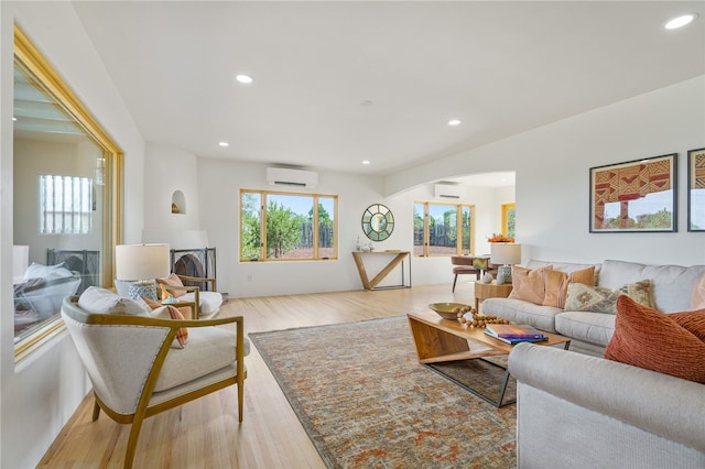 living room with a wall mounted air conditioner and light hardwood / wood-style flooring