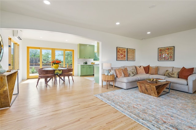 living room featuring a wall mounted AC and light hardwood / wood-style floors