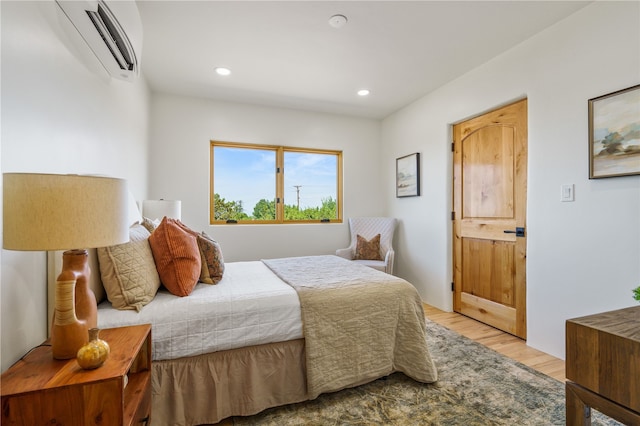 bedroom with a wall mounted air conditioner and light hardwood / wood-style flooring