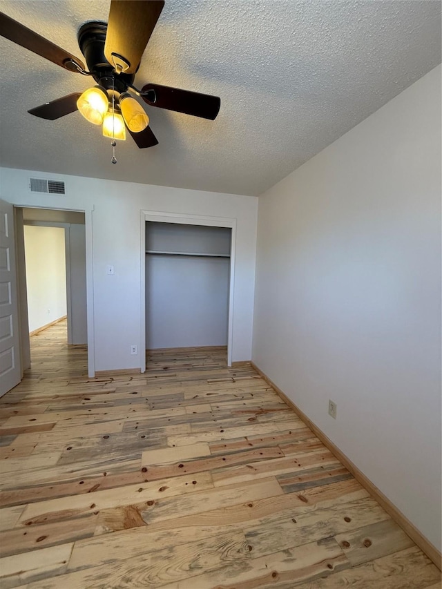 unfurnished bedroom with ceiling fan, a closet, a textured ceiling, and light hardwood / wood-style flooring