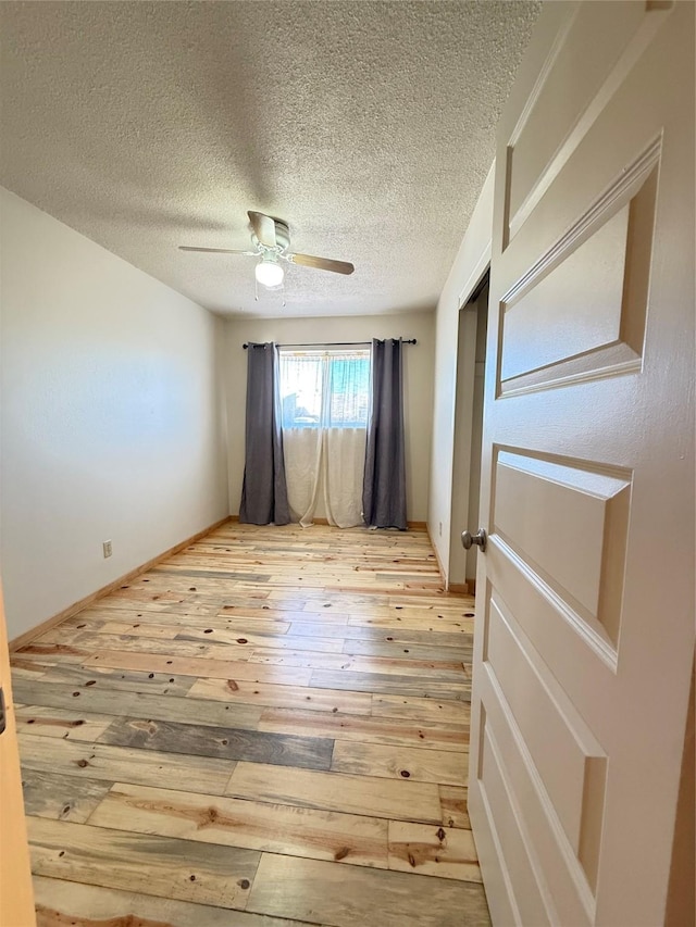 unfurnished room with ceiling fan, light hardwood / wood-style flooring, and a textured ceiling