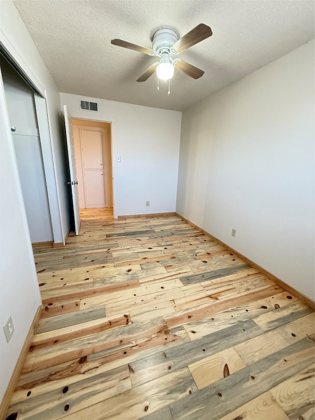 spare room with a textured ceiling, light hardwood / wood-style flooring, and ceiling fan