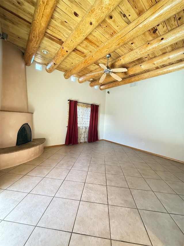 tiled empty room with a large fireplace, ceiling fan, beam ceiling, and wooden ceiling