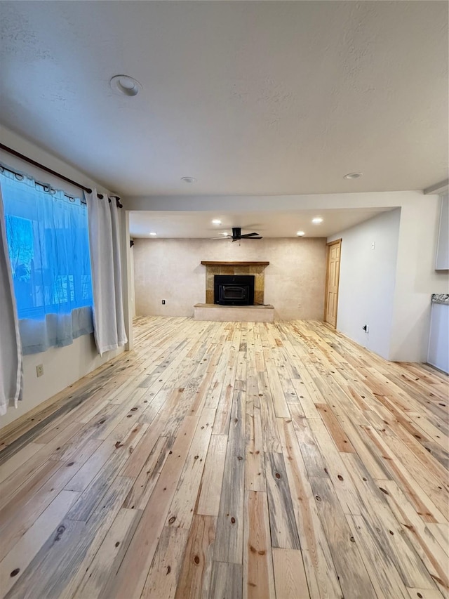 unfurnished living room with a tile fireplace and light hardwood / wood-style flooring