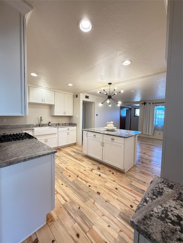 kitchen with pendant lighting, sink, light hardwood / wood-style floors, white cabinetry, and gas cooktop