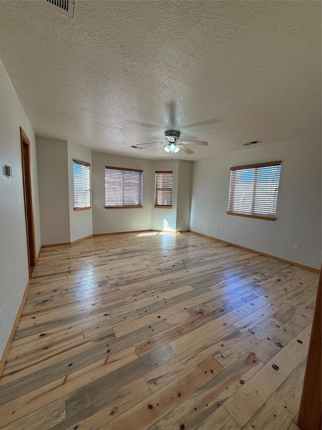 spare room featuring ceiling fan, light hardwood / wood-style floors, and a textured ceiling