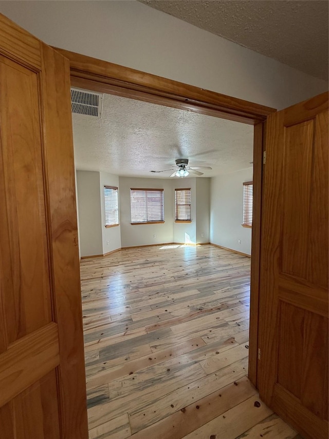 living room featuring a textured ceiling, light hardwood / wood-style flooring, and ceiling fan