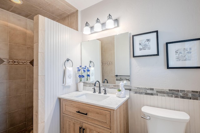 bathroom with vanity, radiator, toilet, tile walls, and a tile shower