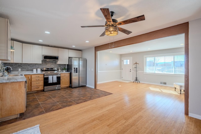 kitchen with dark wood-type flooring, sink, ceiling fan, decorative backsplash, and stainless steel appliances