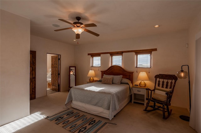 bedroom with light carpet, ceiling fan, and ensuite bath