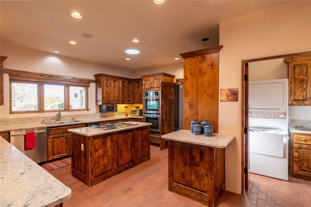 kitchen with stainless steel appliances, stacked washing maching and dryer, sink, and a kitchen island