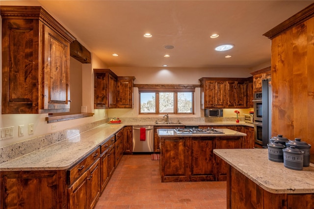 kitchen with light stone counters, sink, a kitchen island, and appliances with stainless steel finishes