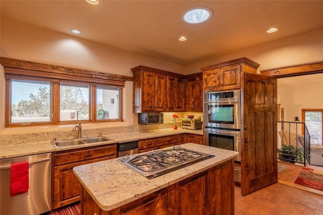 kitchen with light stone countertops, a center island, appliances with stainless steel finishes, and sink