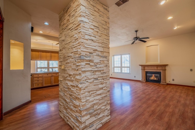 unfurnished living room featuring wood-type flooring, ceiling fan, and a healthy amount of sunlight