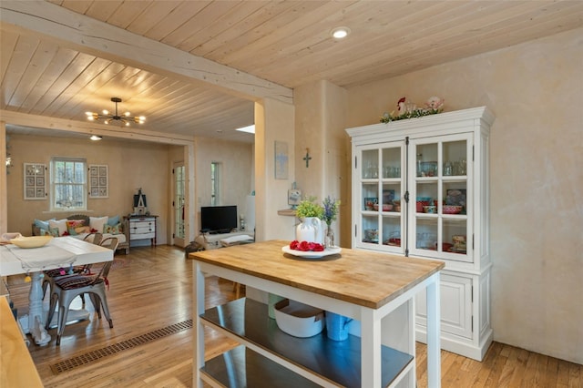 dining room with beamed ceiling, wooden ceiling, light hardwood / wood-style flooring, and a notable chandelier